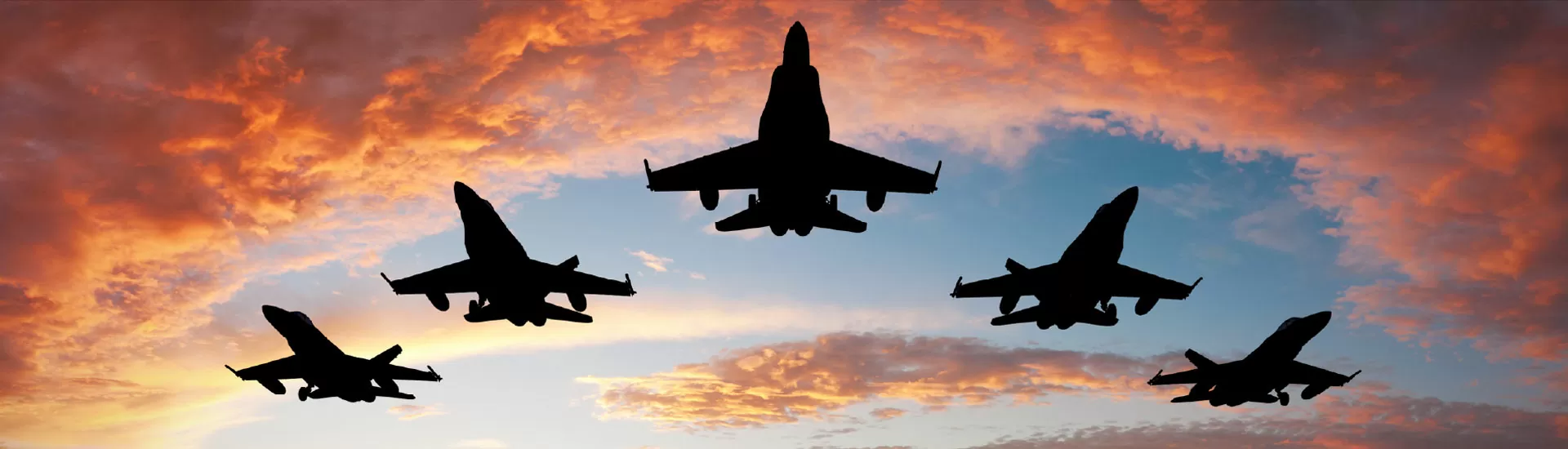 Five fighters flying at sunset